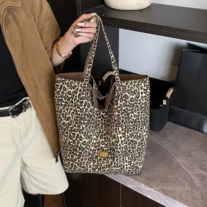Fashionable large leopard print canvas tote bag held by a person in casual attire.