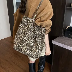 Detailed view of large leopard print canvas tote bag carried on shoulder by model