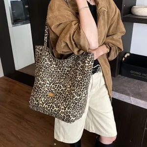 Detailed view of a large leopard print canvas tote bag being carried by a stylish model
