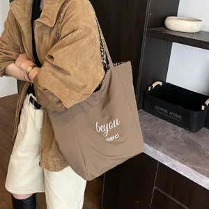 Brown canvas tote bag with leopard lining and merci print detail worn by a model
