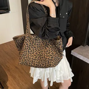 Large leopard print canvas tote bag worn by a model in a stylish casual outfit