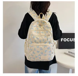 Back view of a female student wearing a cream-colored backpack with a blue bow pattern design