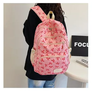 Detailed view of a pink backpack with red ribbon patterns and a 'Hello weekend' patch