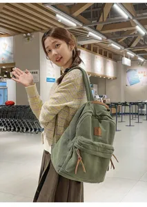 Zaino in velluto a coste verde alla moda per studenti indossato da una modella in interni