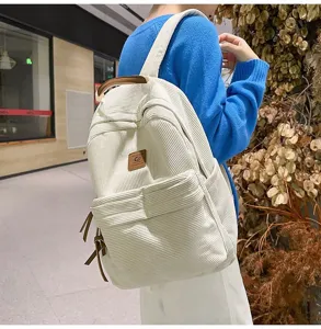 Vista dettagliata di un elegante zaino in velluto a coste bianco con dettagli in pelle marrone