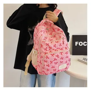 Lifestyle detail of a pink backpack with red bow patterns on a student model