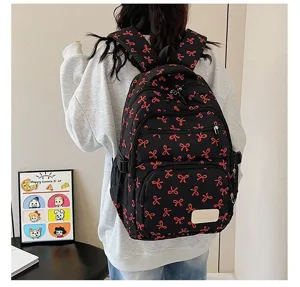 Detail of a stylish black backpack with red bow patterns worn by a female student