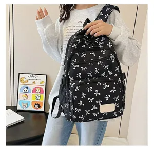 Detailed view of stylish black backpack with white bow pattern worn by a young woman