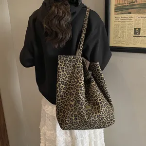 Back view of a large leopard print canvas tote bag styled with a casual black hoodie