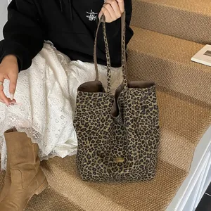 Close-up detail of a large leopard print canvas tote bag held by a model on stairs