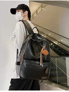 Black vintage faux-leather backpack with cute teddy bear charm worn by a model in a mall