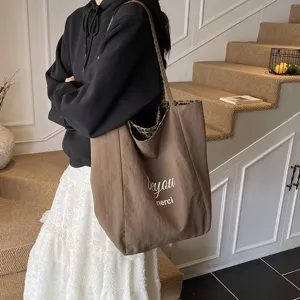 Large brown canvas tote bag with leopard print interior carried by a model in casual style