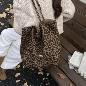 Detailed view of a large leopard print canvas tote bag on a park bench in an autumn setting.