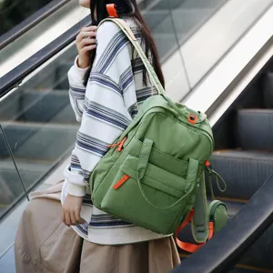 Grand sac à dos de banlieue vert résistant à l'eau avec des accents orange porté à l'extérieur