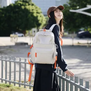 Sac à dos commuteur beige déperlant avec sangles orange dans un cadre de vie extérieur.
