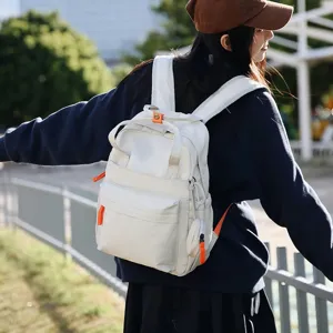 Jeune fille asiatique portant un sac à dos de voyage blanc imperméable dans un parc