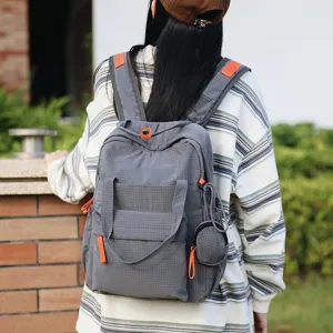 Vue arrière d'un sac à dos gris imperméable porté par un mannequin dans un cadre extérieur.