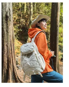 Asiatin mit Kamera trägt einen cremeweißen Nylon-Wanderrucksack in einem üppigen Wald