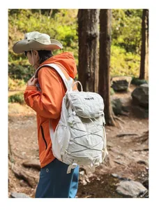 Detailansicht eines leichten weißen Wanderrucksacks, getragen von einem Reisenden im Wald.