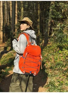Großer orangefarbener Wanderrucksack aus Nylon, getragen von einer Wanderin im Waldgebiet