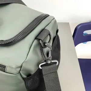 Gros plan sur les details du sac de sport vert avec crochet en metal robuste et poche en filet.