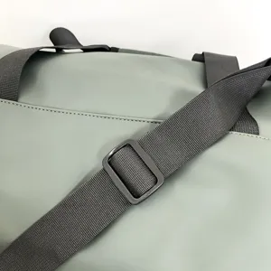 Vue détaillée de la sangle de la bandoulière de sac de voyage de fitness vert clair.