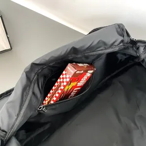 Détail intérieur de sac de voyage noir, grand sac de sport avec poche zippée pratique.
