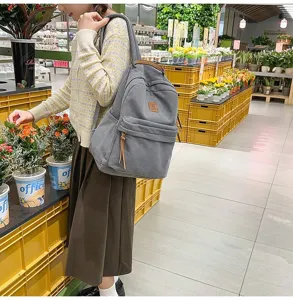 Zaino in velluto a coste grigio indossato a spalla, dallo stile campus casual e trendy