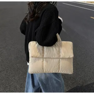 Vista dettagliata di una borsa tote trapuntata beige portata all'aperto.
