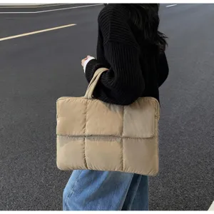 Grande borsa tote trapuntata color kaki indossata da una modella su strada asfaltata