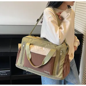 Detailed view of an olive green travel duffle bag worn on a model's shoulder in style.