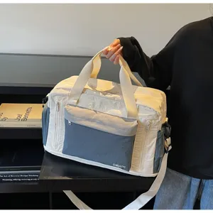 Close-up of large cream and grey travel duffel bag held by a hand on a shelf.