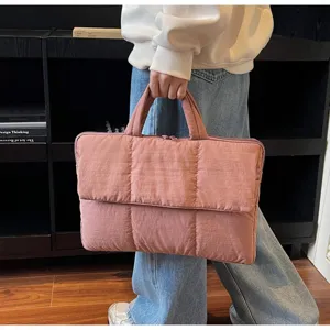 Dettaglio di una borsa per laptop trapuntata rosa con manico in un ambiente lifestyle