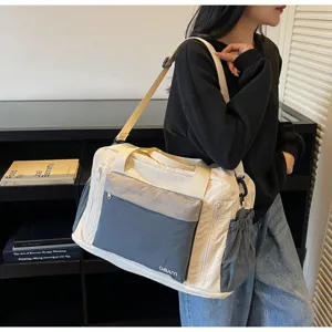 Cream and grey large travel duffel bag shown on shoulder in indoor lifestyle shot