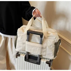 Cream travel duffle bag with a trolley sleeve secured on a white suitcase handle