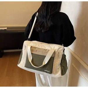 Detail view of a large olive and cream travel duffel bag worn as a shoulder bag