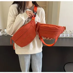 Details of orange canvas crossbody chest bags with embroidered studio logo text