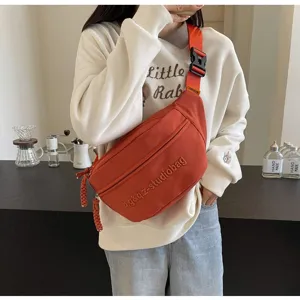 Casual orange crossbody chest bag worn by a model in a cozy indoor lifestyle setting