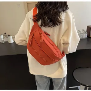Detail view of a bright orange multi-functional chest bag worn on a model's back