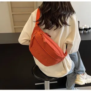 Detail view of orange nylon crossbody chest bag with adjustable strap and zipper closure