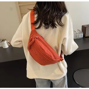 Rear view of stylish orange nylon fanny pack worn across a casual white sweatshirt