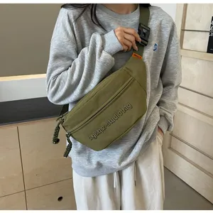 Close-up view of the olive green minimalist crossbody bag worn with a casual grey sweatshirt.