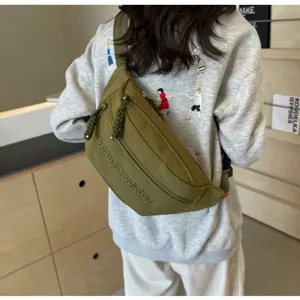 Olive green minimalist nylon crossbody fanny pack worn by a model in a casual setting