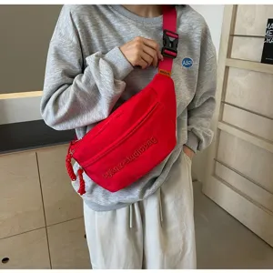 Close-up of a minimalist red functional crossbody chest bag for casual sports style.