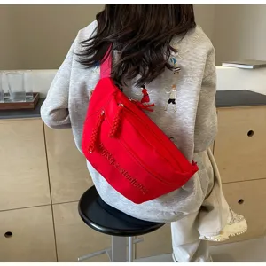 Detailed back view of a vibrant red minimalist chest bag worn over a casual grey sweatshirt