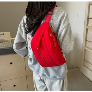 Close-up rear view of a red minimalist crossbody chest bag worn by a female student