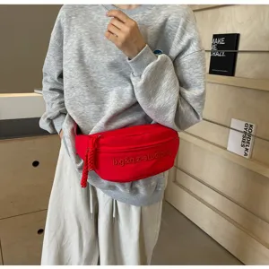 Macro view of a vibrant red minimalist chest bag with embroidery on a grey sweatshirt