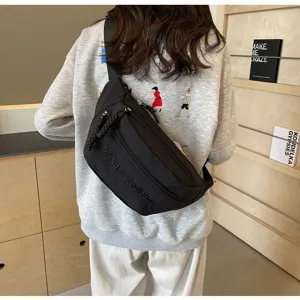 Black minimalist nylon crossbody chest bag worn by model in a casual indoor setting