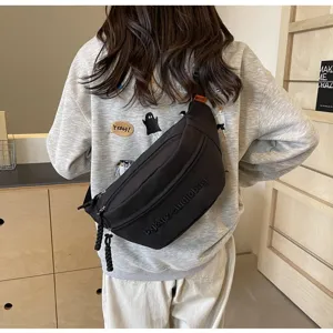 Back view of a black minimalist crossbody chest bag worn over a casual grey sweatshirt