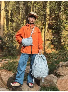 Asiatisches Model mit hellblauem Nylon-Rucksack mit Kordelzug in einer Wanderwaldszene